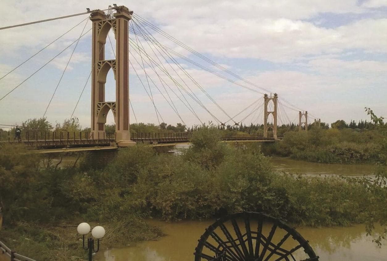 ASSAS Group, Syria. Deir ez Zor suspension bridge: Riverbank view of the suspension bridge, showing its towers, cables and spans.
